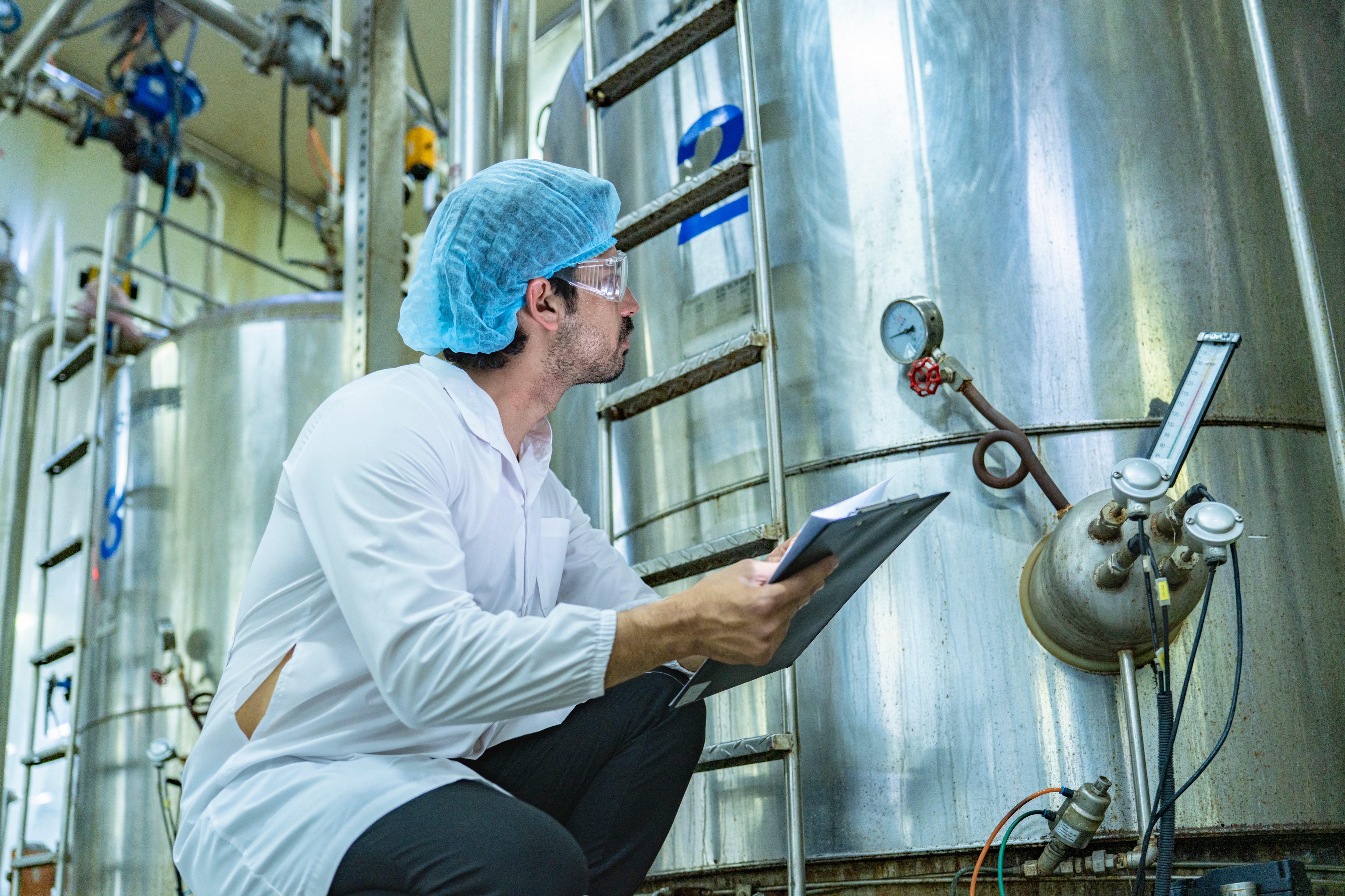 Technician insepcting large industrial tanks